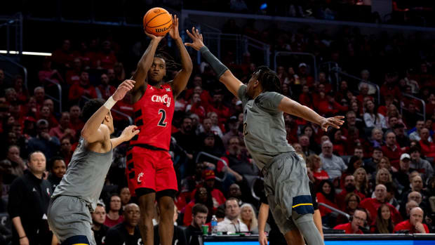 Cincinnati Bearcats guard Jizzle James (2) hits a jump shot over West Virginia Mountaineers defenders in the second half of the NCAA basketball game between Cincinnati Bearcats and West Virginia Mountaineers at Fifth Third Arena in Cincinnati on Saturday, March 9, 2024.